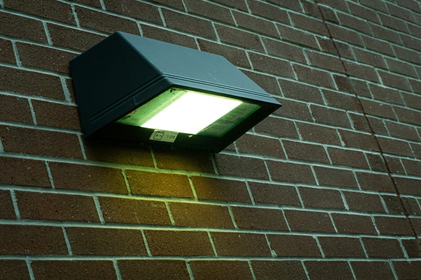 Exterior wall-mounted light fixture on a brick commercial building — property management and building systems